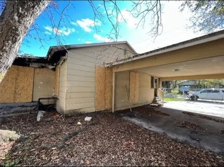 A boarded-up house with a damaged roofline — the kind of property we buy as-is